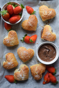 Pastries on a tray with chocolate spread and strawberries.