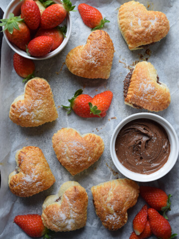 Pastries on a tray with chocolate spread and strawberries.