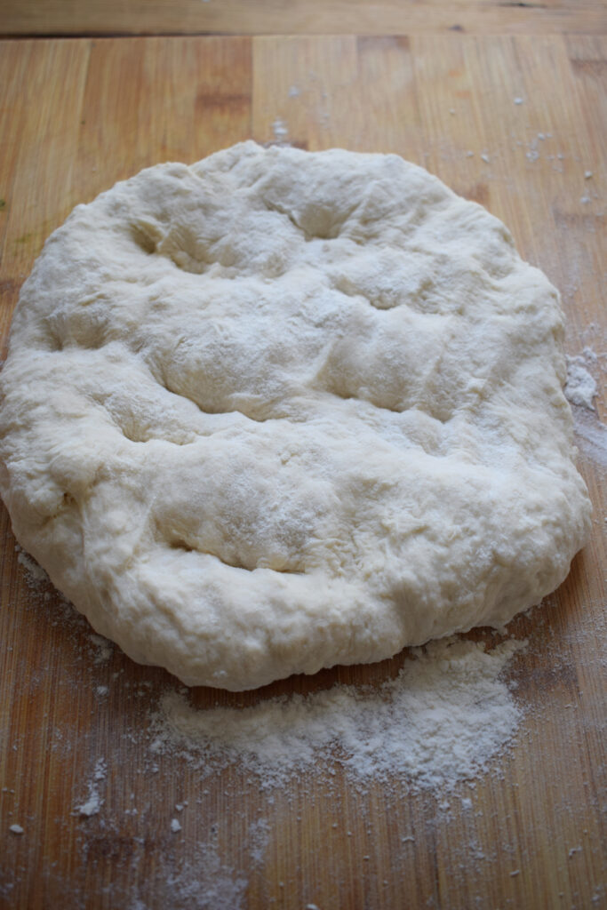 Flattened dough on a wooden board.