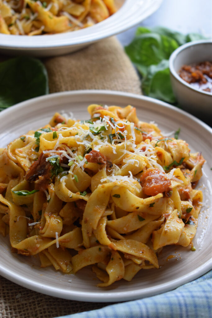 Close up of tagliatelle on a plate with red pesto.