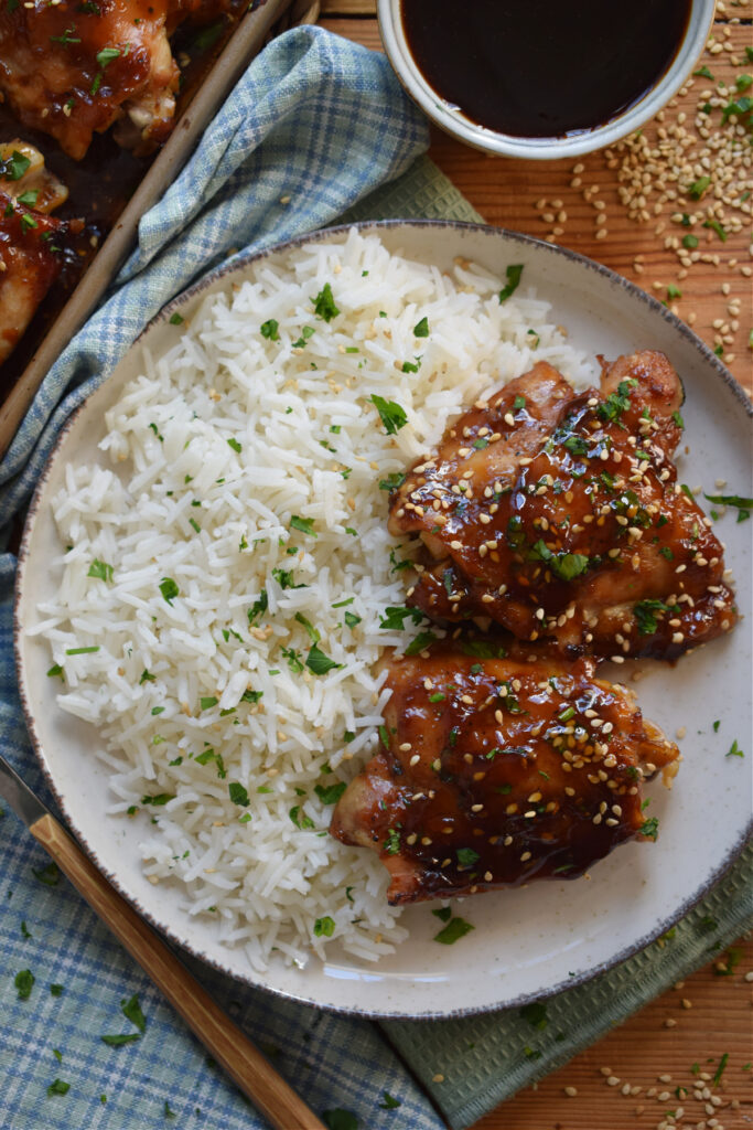 Chicken thighs on a plate with white fluffy rice.