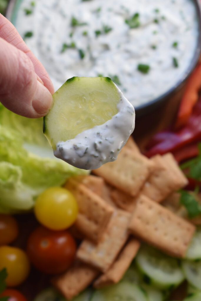 Close up of a cucumber dipped in Ranch dip.
