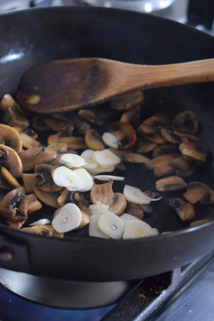 Add garlic to a skillet with mushrooms.