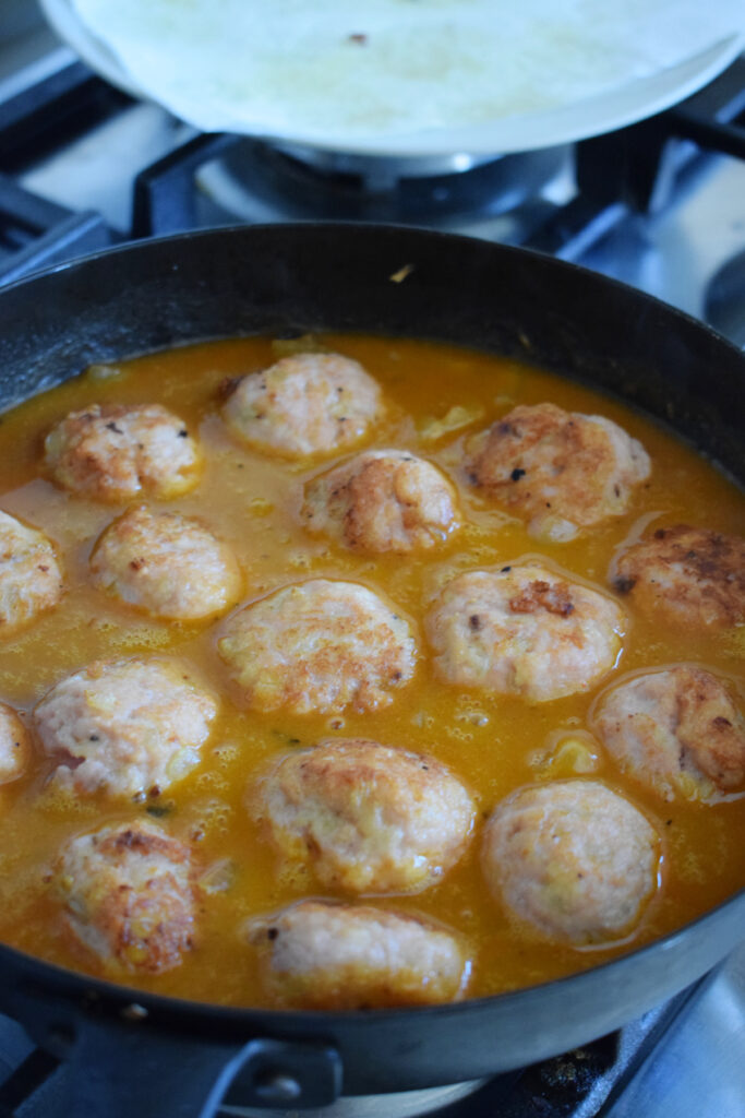 Meatballs in a skillet with stroganoff sauce.