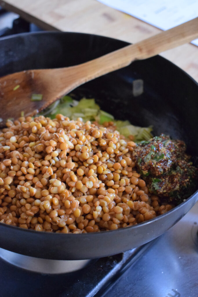 Lentils in a skillet with herb butter and leeks.