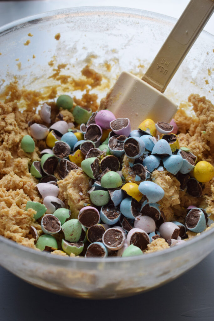 Adding candy to cookie dough.