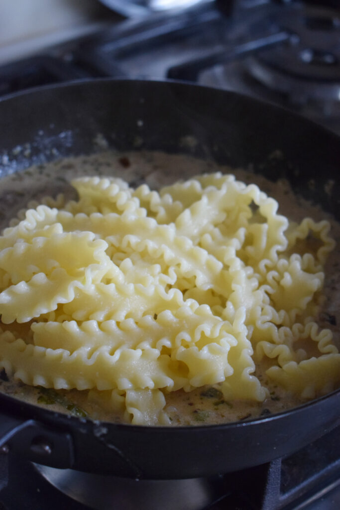 Pasta in a skillet with a creamy ricotta sauce.
