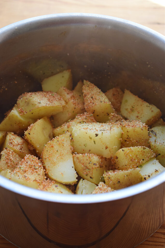 Parboiled potatoes in a saucepan with seasoning.