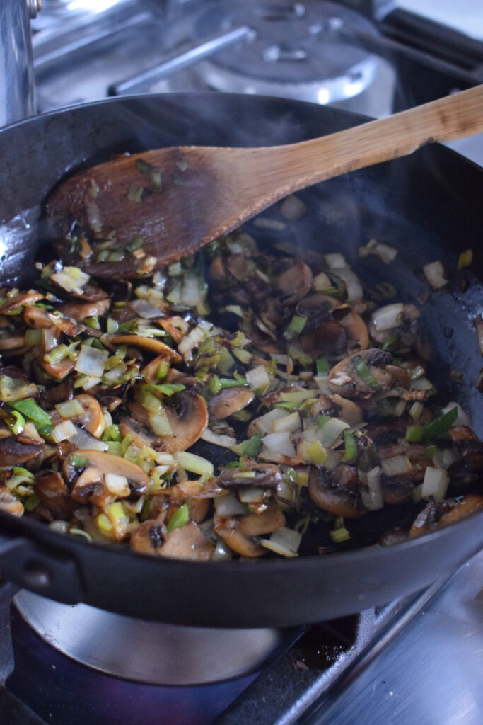 Cooking leeks and mushrooms in a skillet.
