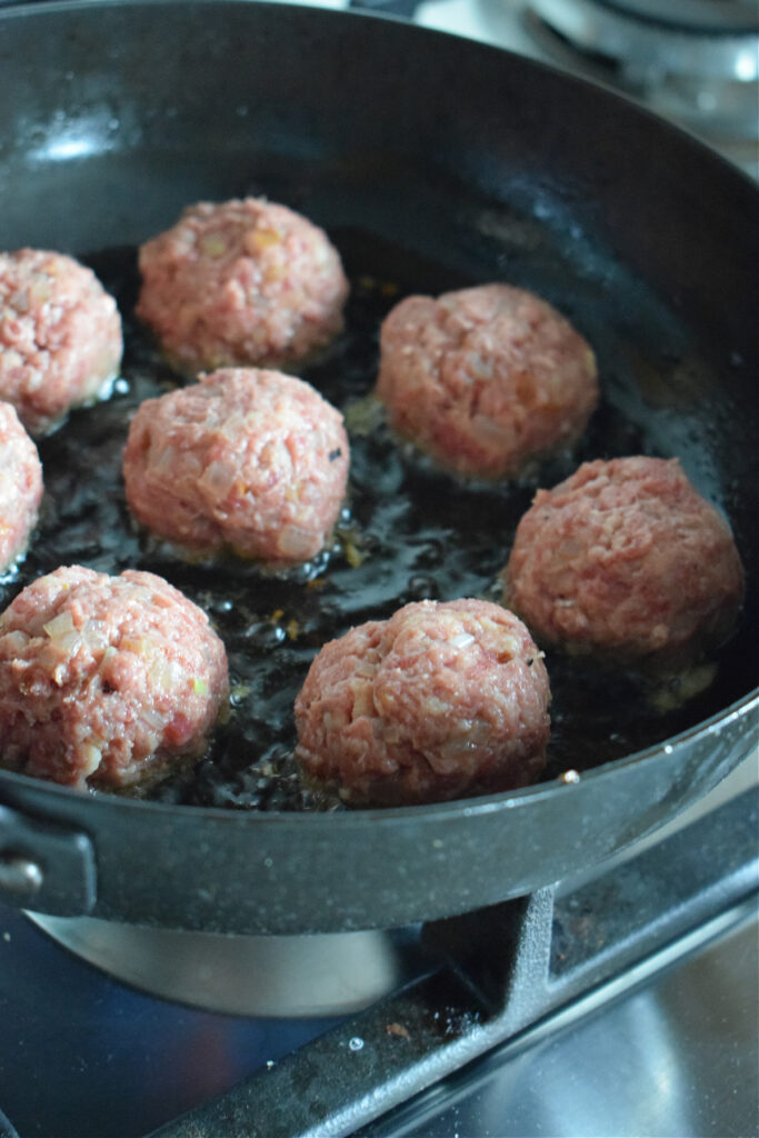 Browning meatballs in a skillet.