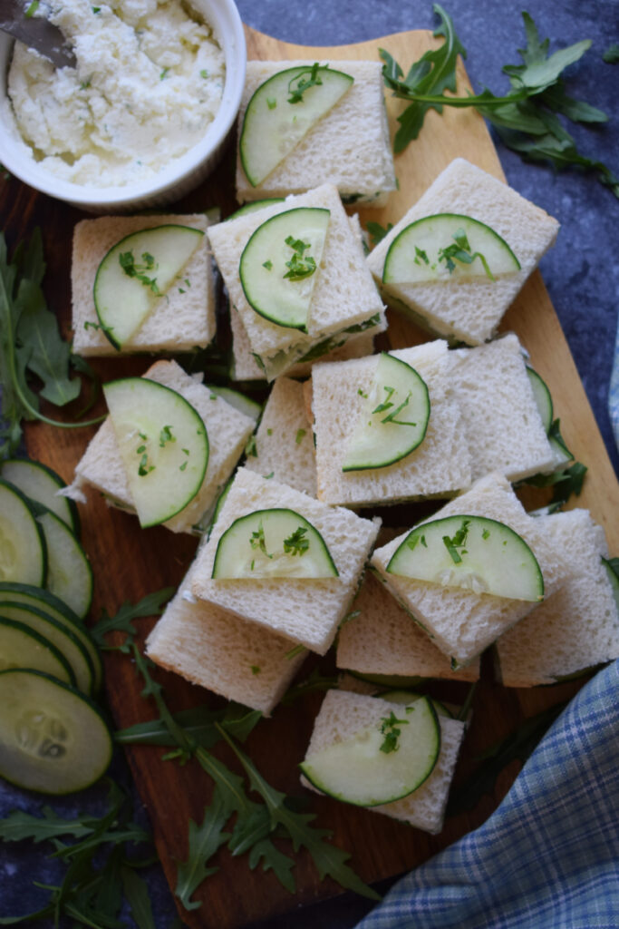 Cucumber sandwiches on a wooden board.