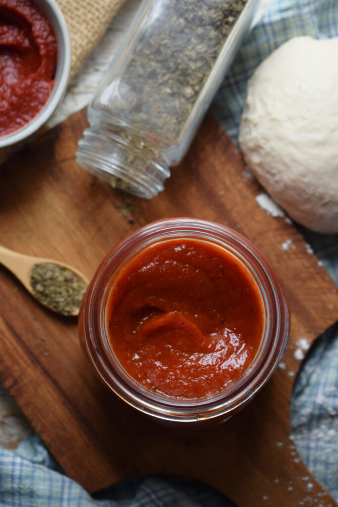 Homemade pizza sauce in a jar with dough.