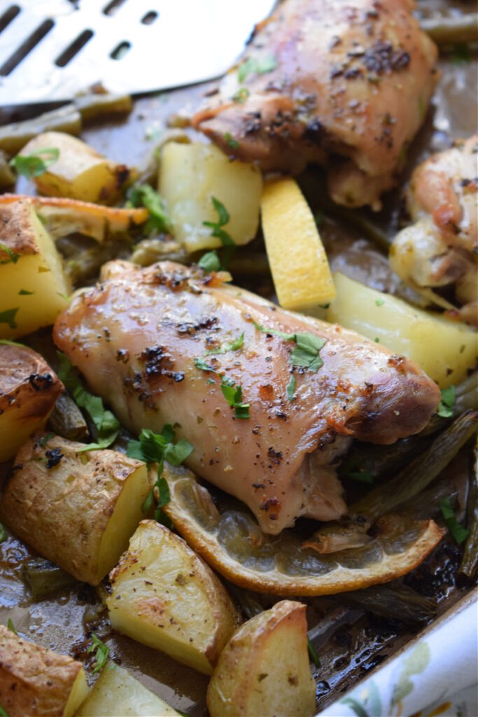 Chicken thighs and potatoes on a baking tray.