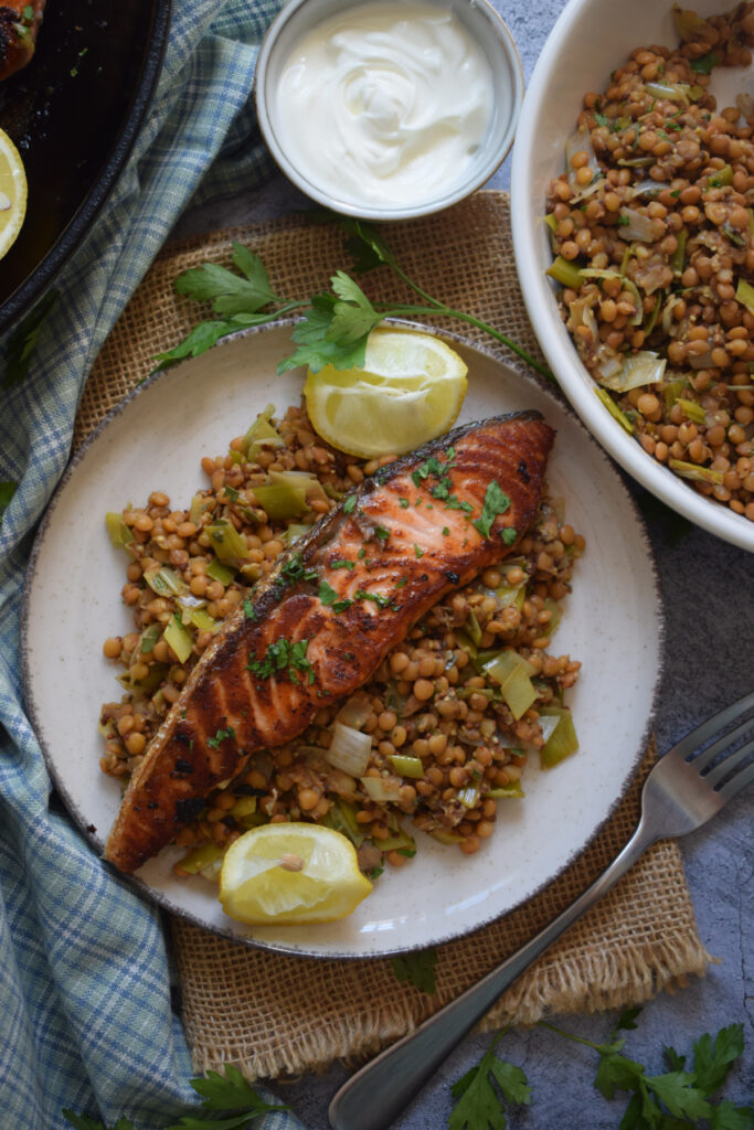 Salmon with lentils and lemon wedges.