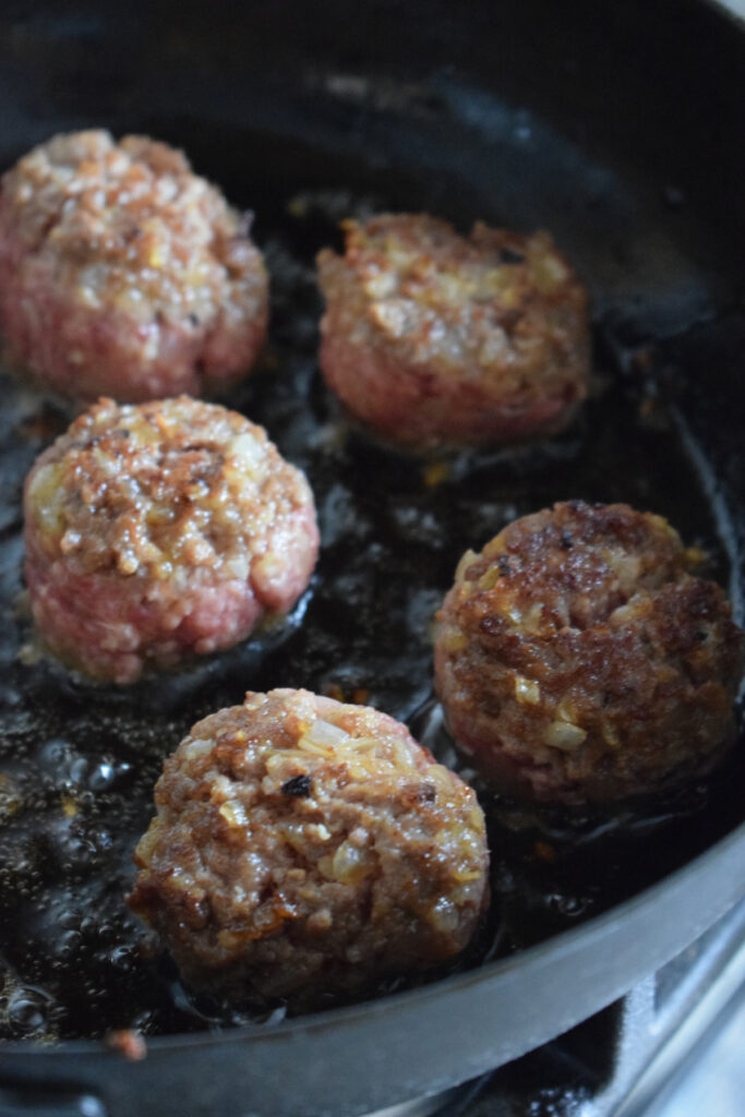 Browning meatballs in a skillet.