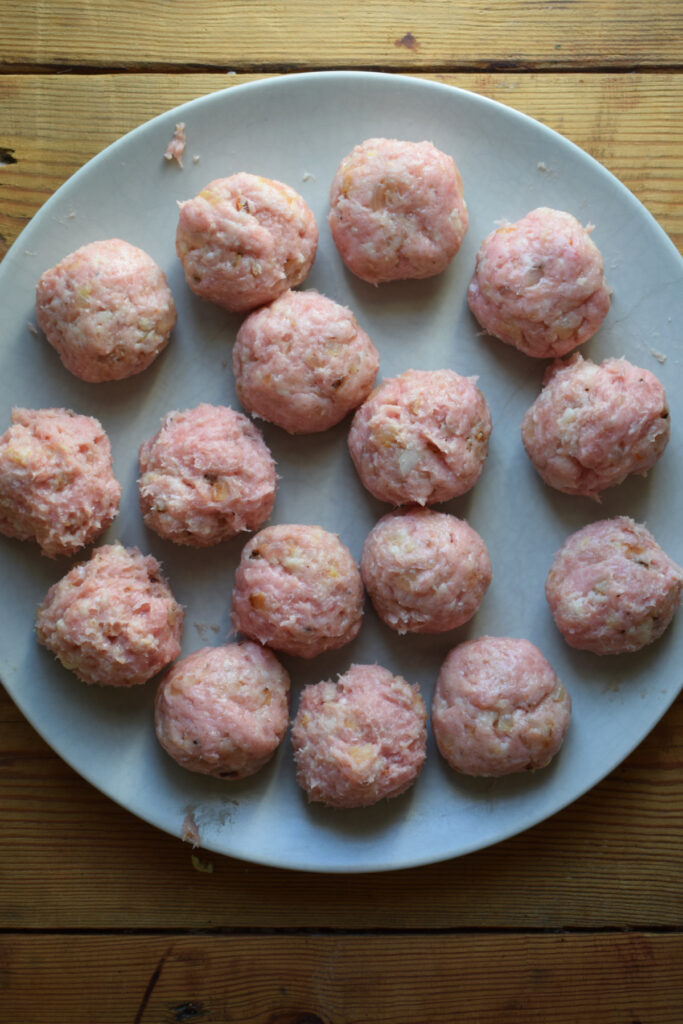 Uncooked meatballs on a plate.