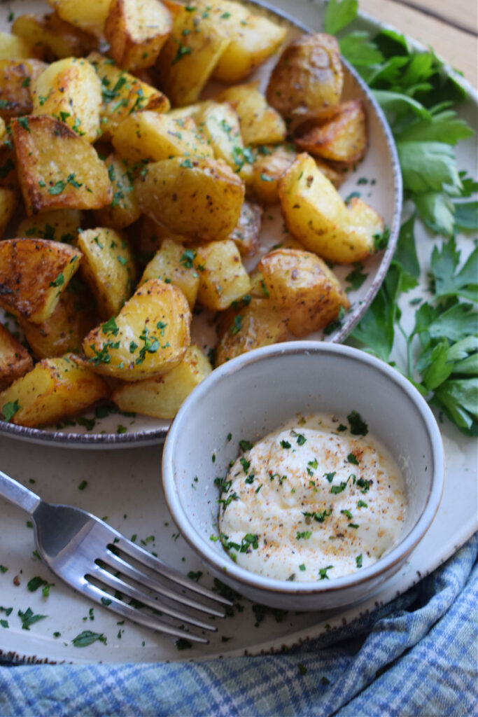 Potatoes on a serving plate with a dipping sauce.