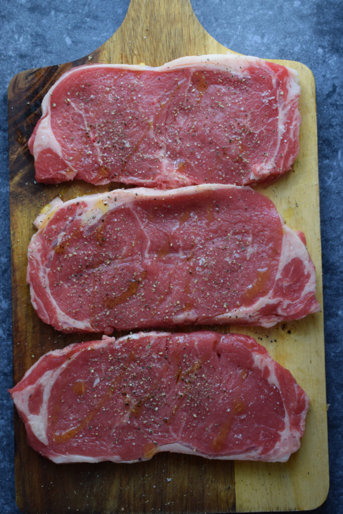 Seasoned steak on a wooden board.