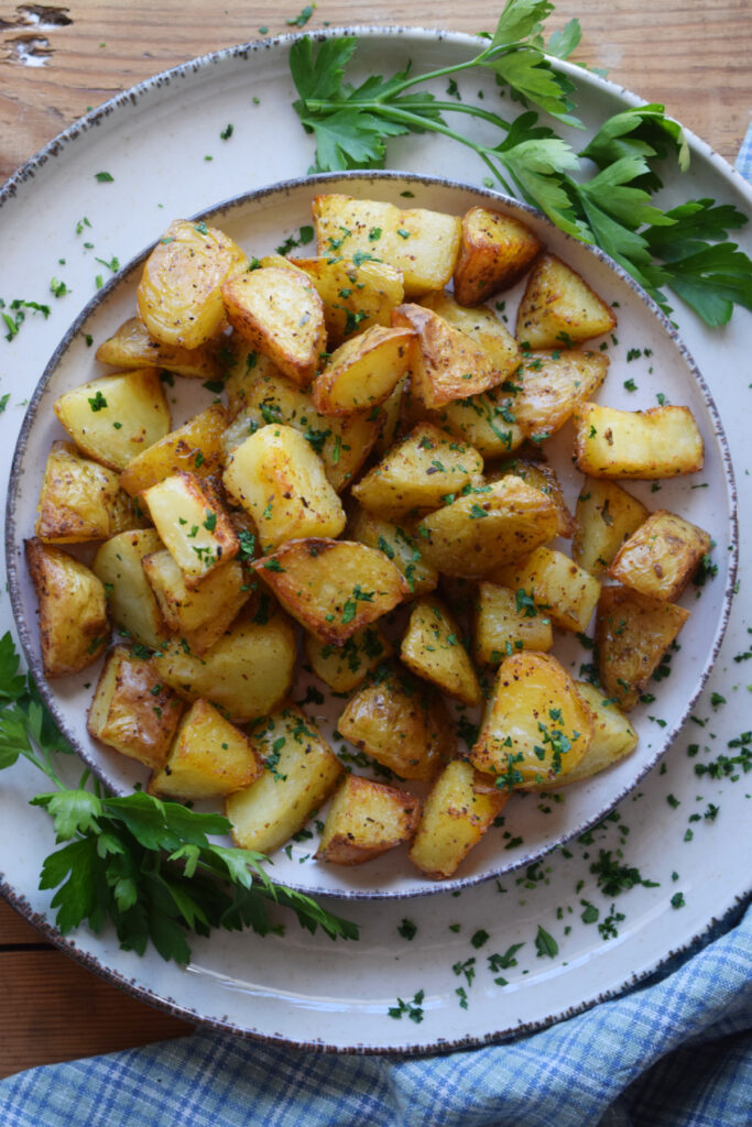 Roasted potatoes on a plate with fresh parsley.