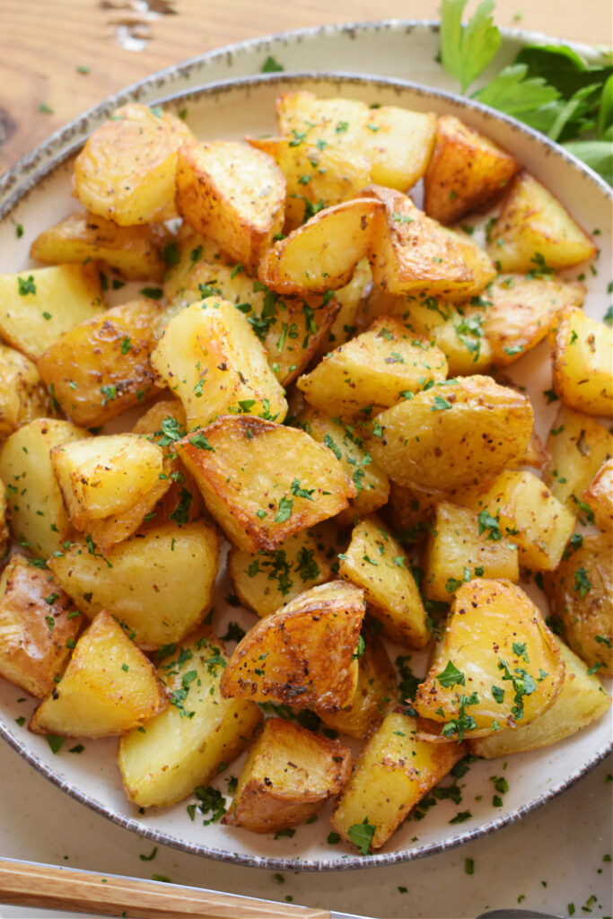 A plate of crispy potatoes topped with fresh herbs.