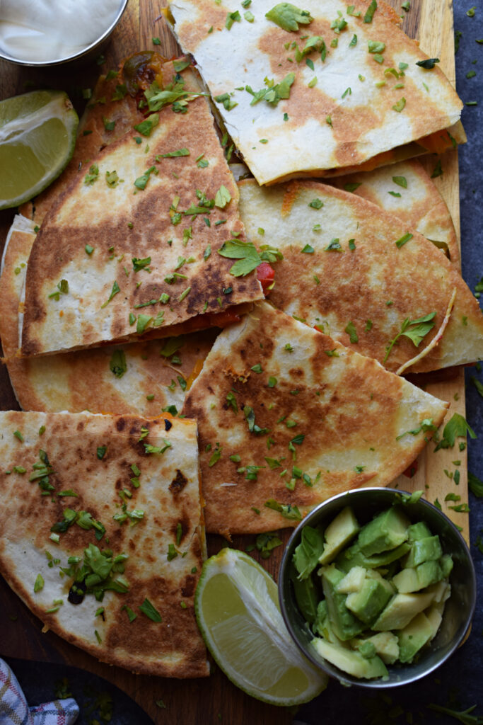 Roasted bell pepper quesadillas on a tray with avocado.