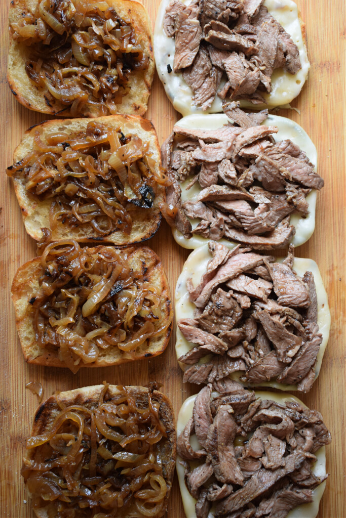 Bread rolls topped with caramelized onions and shaved steak.