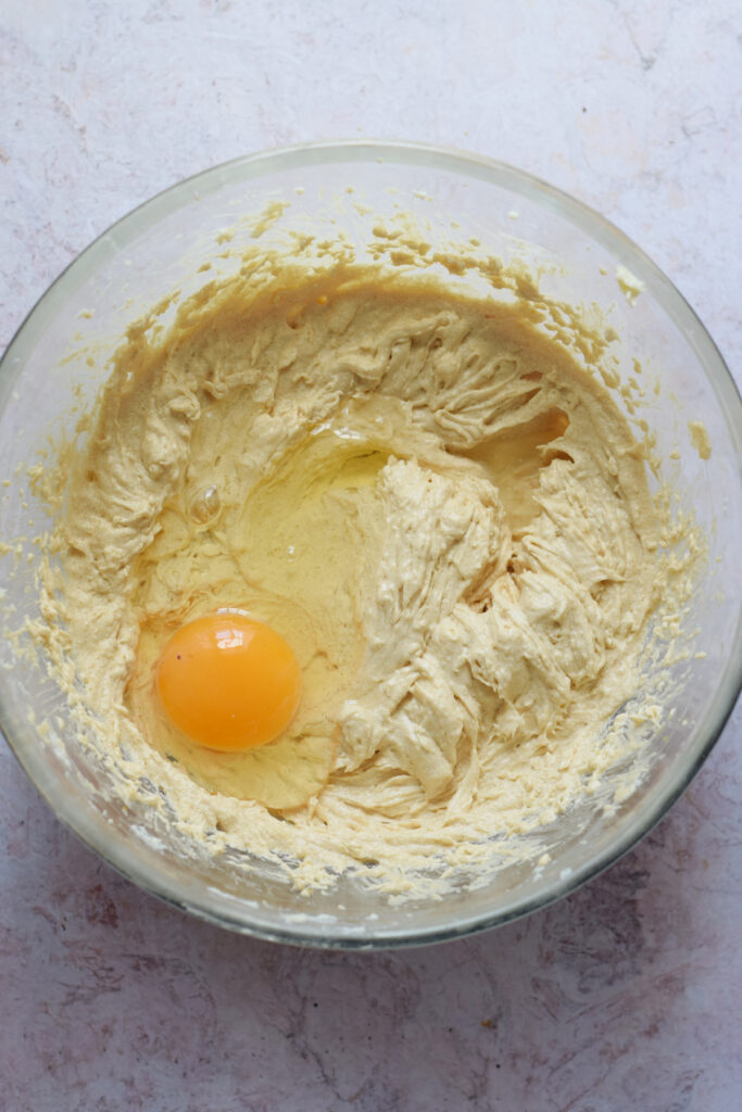 Adding egg to cookie batter.