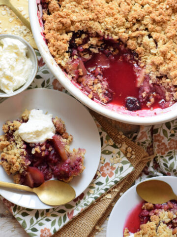 Apple crisp and mixed berry crumble in a serving bowl and on serving plates.