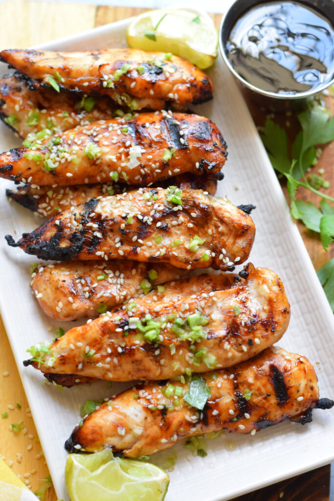 Grilled teriyaki chicken tenders with limes and sesame seeds.