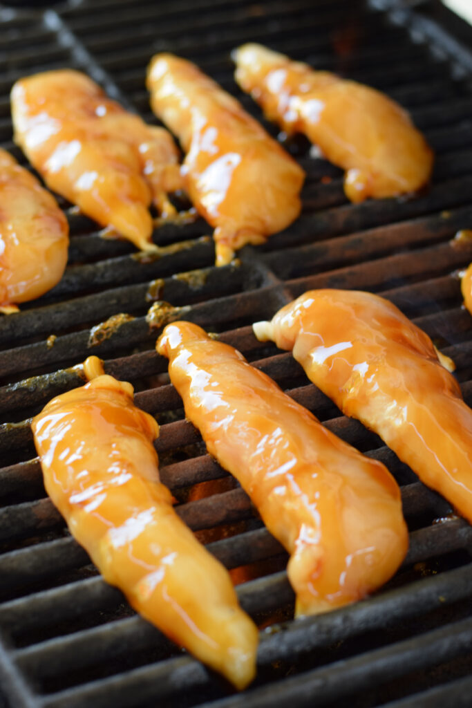 Cooking chicken tenders on a grill.