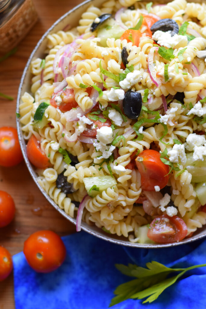 Pasta salad in a bowl with fresh vegetables.