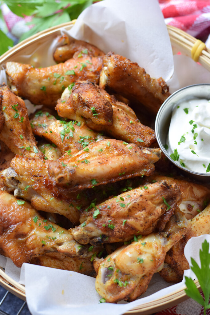 Crispy chicken wings in a basket with a dip.