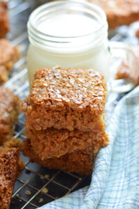 A stack of flapjacks with a glass of milk.