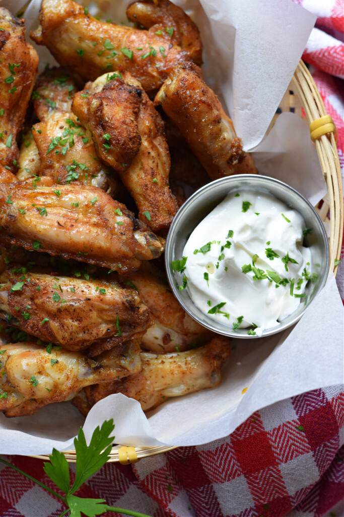 Close up of wings in a basket with a yogurt dip.
