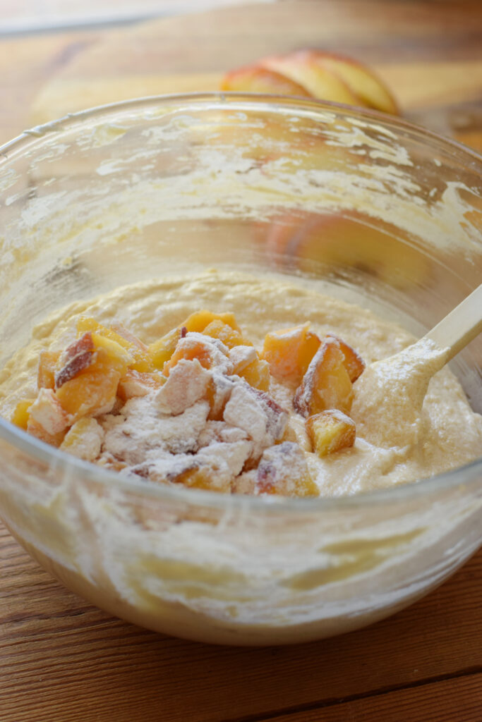 Adding diced peaches to cake batter.