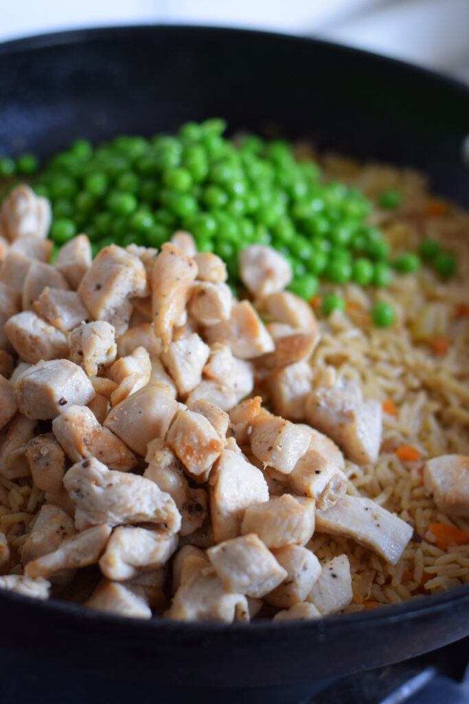 Adding chicken and peas to a skillet.