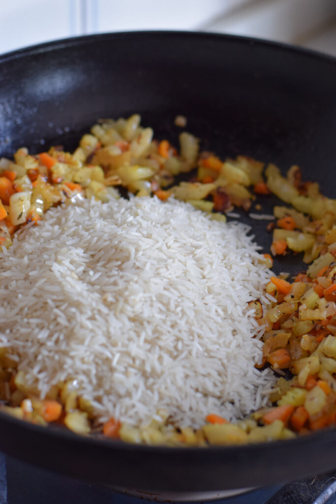 Adding uncooked rice to a skillet.
