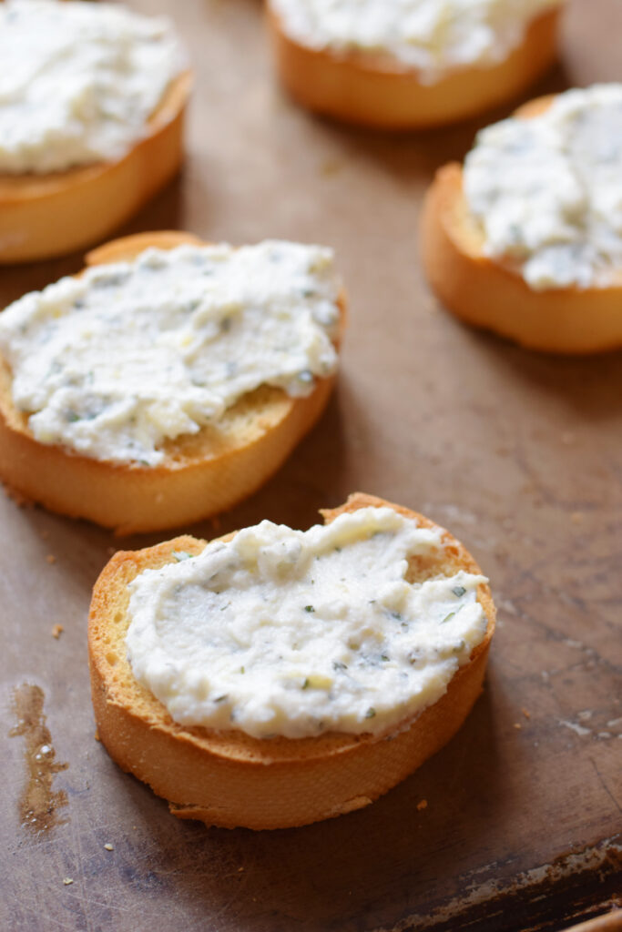 Ricotta cheese on top of baguette bread slices.