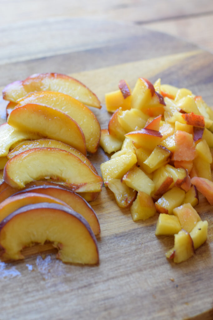 Sliced and cut peaches on a wooden board.