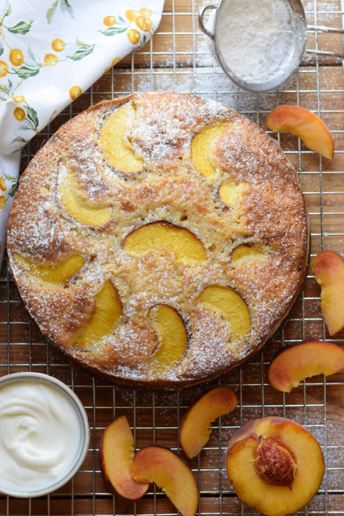 A peach cake on a baking tray with slices of peaches.