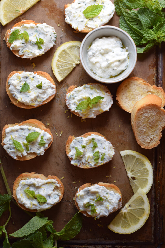 A tray with ricotta cheese bruschetta with fresh mint.