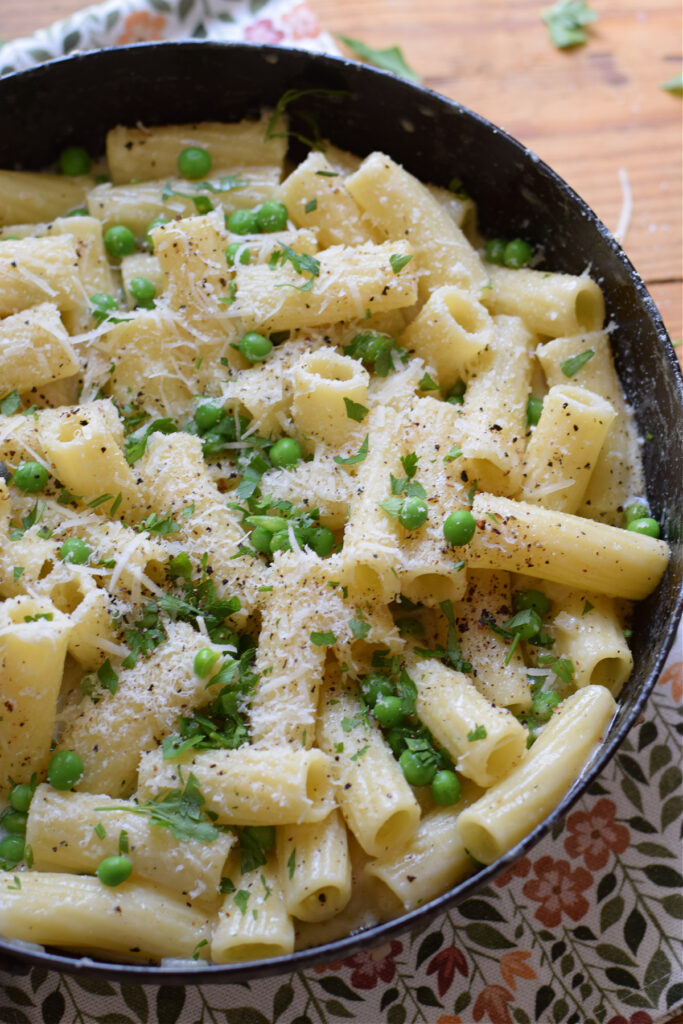 Pasta with parmesan and peas in a skillet.