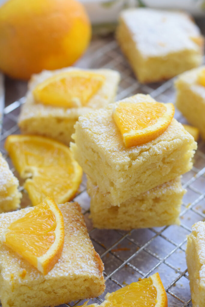 Orange cake squares stacked in a pile.