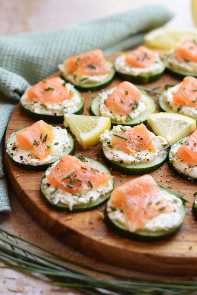 Cucumber smoked salmon bites on a wooden tray.