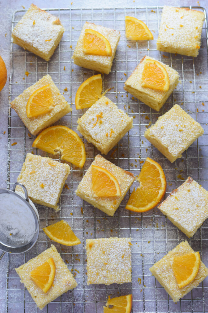 Orange cake squares on a baking rack.