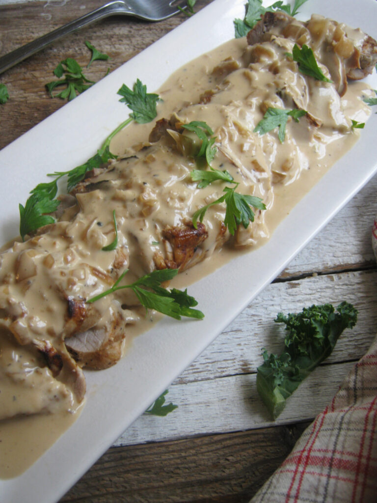 Pork with a creamy sherry sauce on a white serving plate.