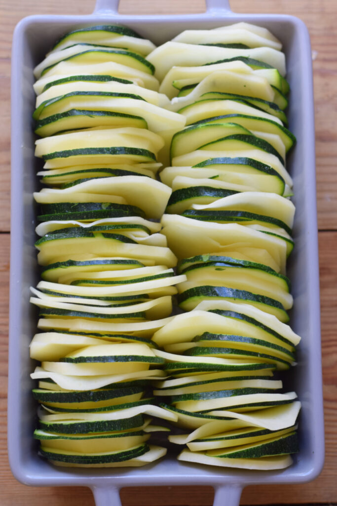Potato and zucchini slices in a casserole dish.