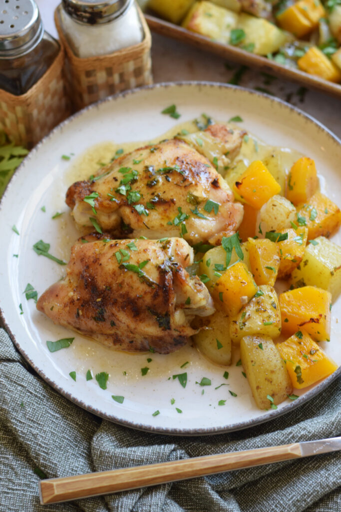 Seasoned chicken thighs, squash and potatoes on a plate.