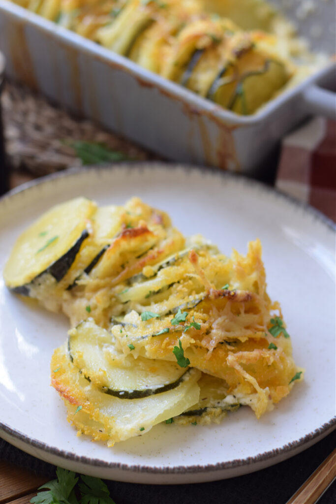 Close up of a potato and zucchini gratin on a plate.