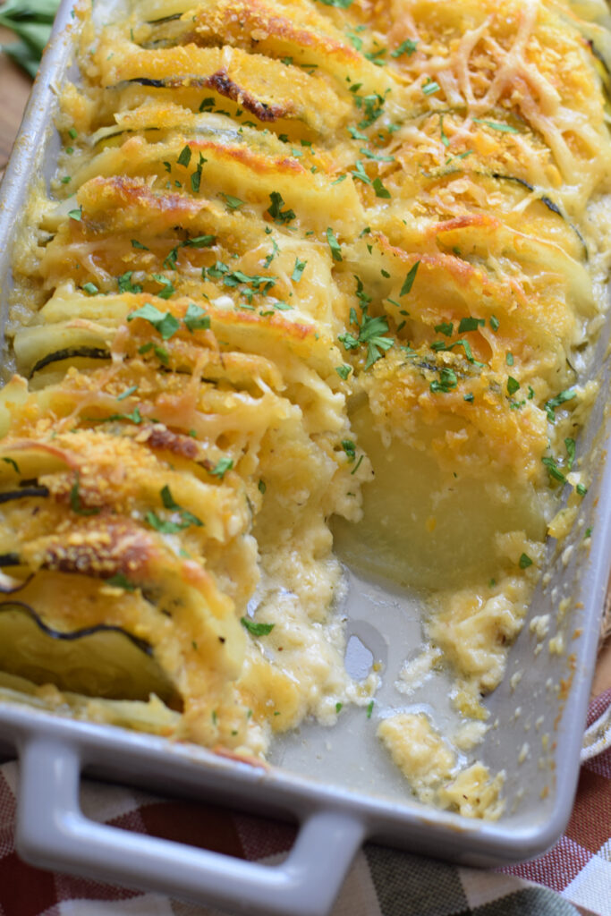 Close up of potato zucchini bake in a casserole dish.